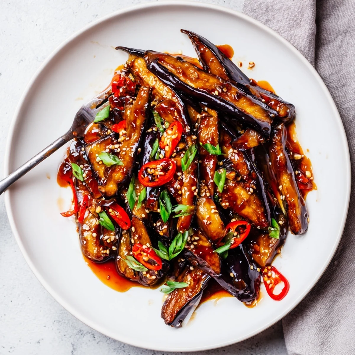 Steaming Sichuan Style Braised Aubergines served over jasmine rice, garnished with scallions