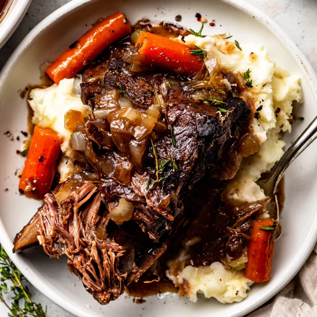 A bowl of Slow Cooker Beef Short Ribs, fall-off-the-bone, with carrots