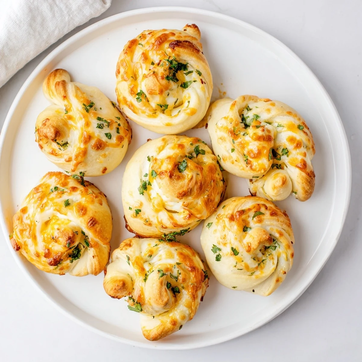 Eight baked appetizers featuring gooey cheese filling and rich garlic butter coating on a baking sheet