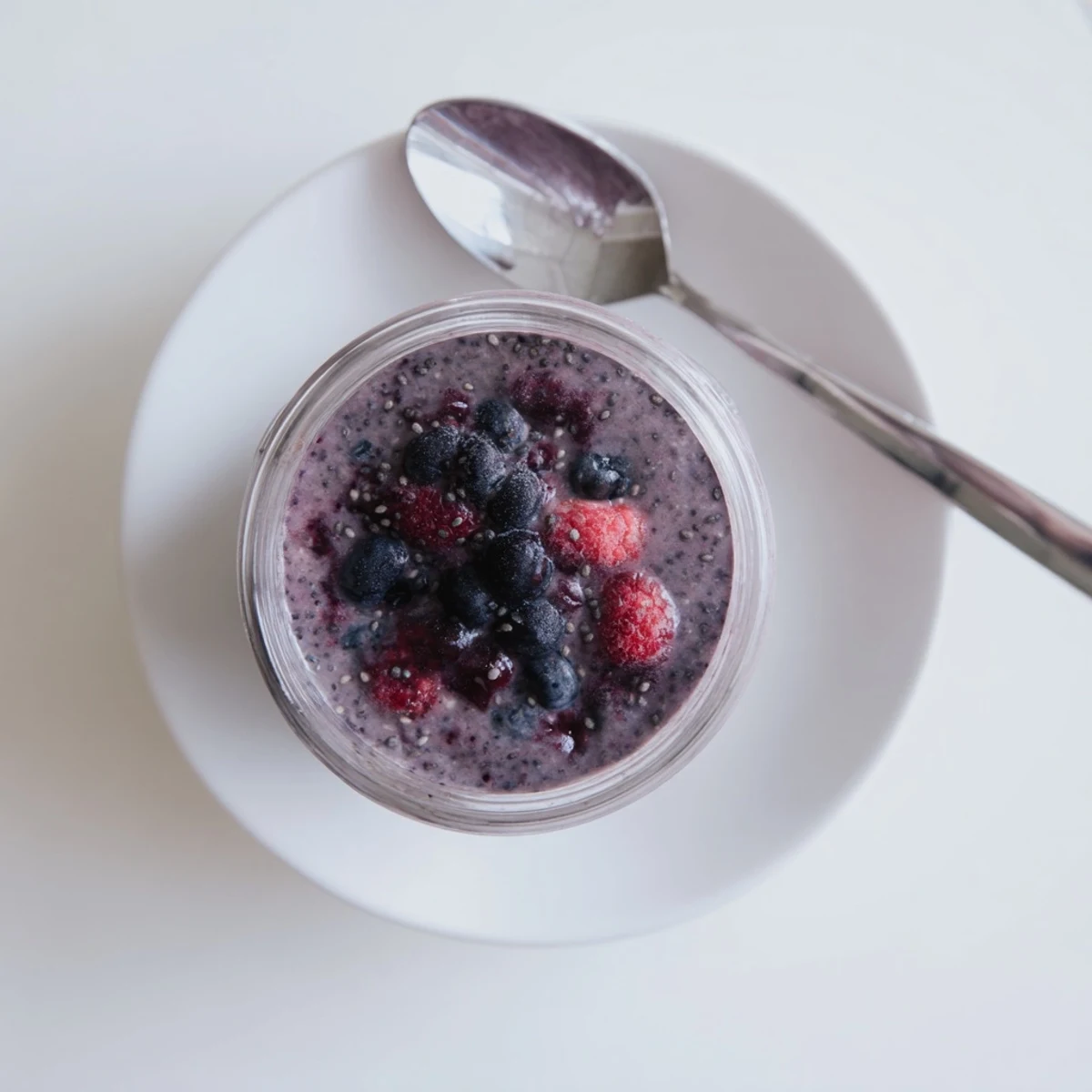 Creamy chia seed smoothie topped with fresh berries in a clear glass
