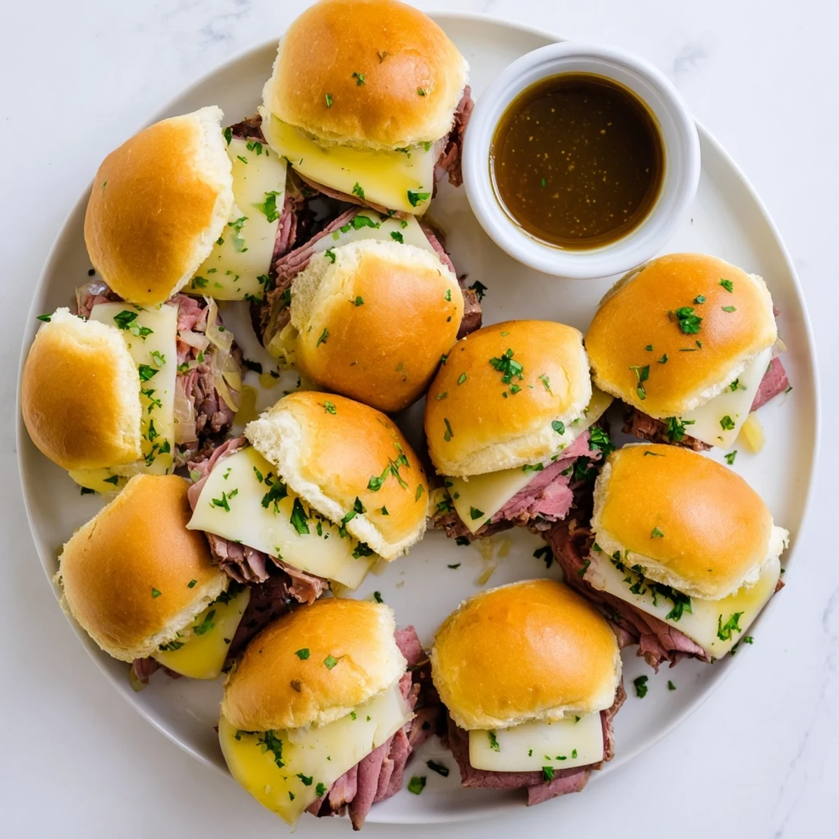 Golden French dip sliders with melted provolone and caramelized onions on toasted brioche buns