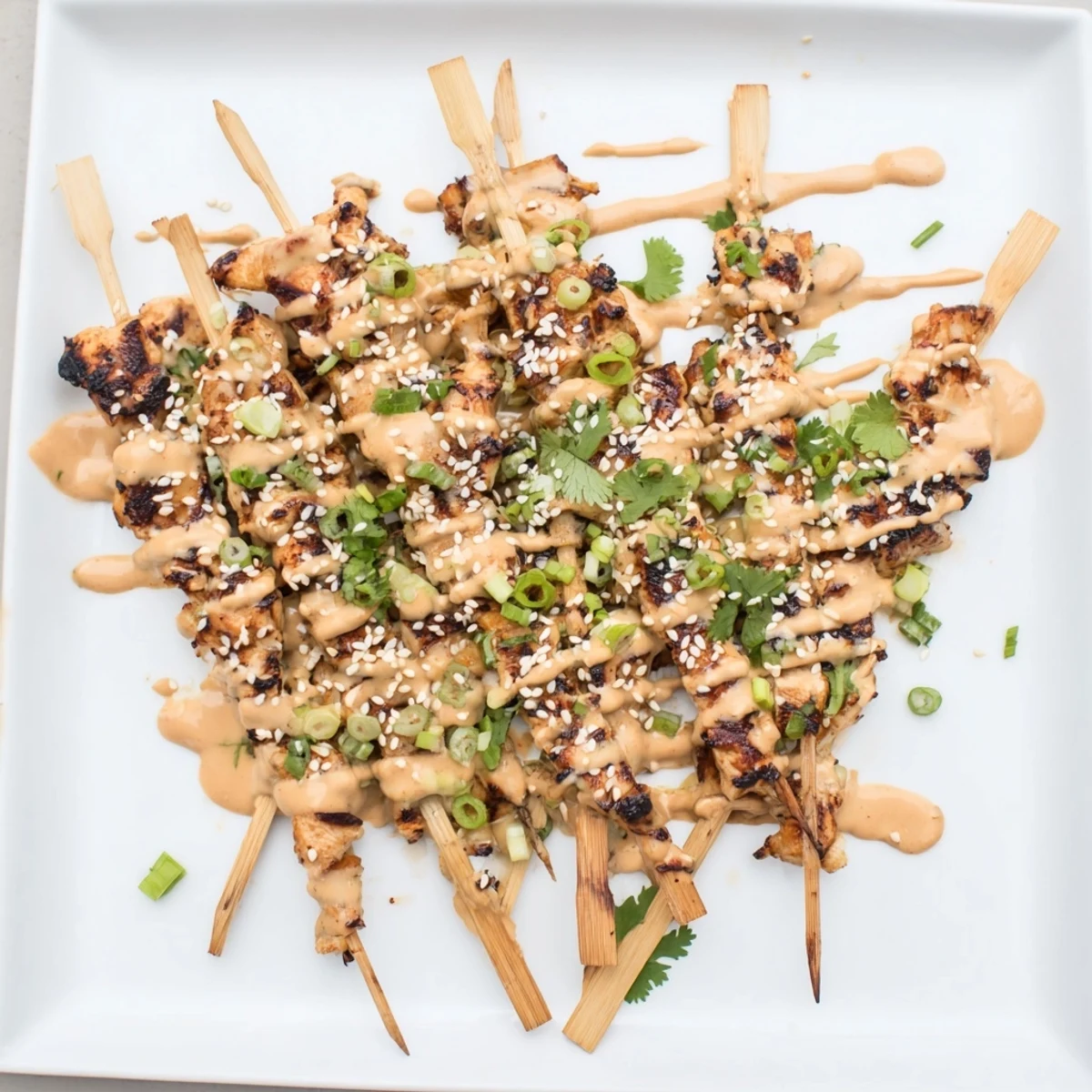 Juicy grilled Bang Bang Chicken Skewers coated in creamy spicy sauce with sesame seed garnish