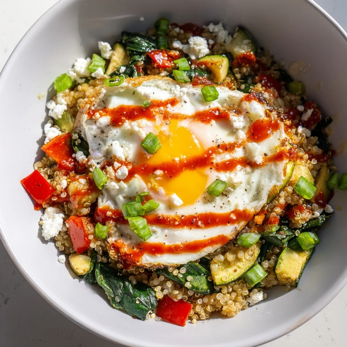 Warm savory quinoa breakfast bowl topped with a runny egg and sautéed vegetables