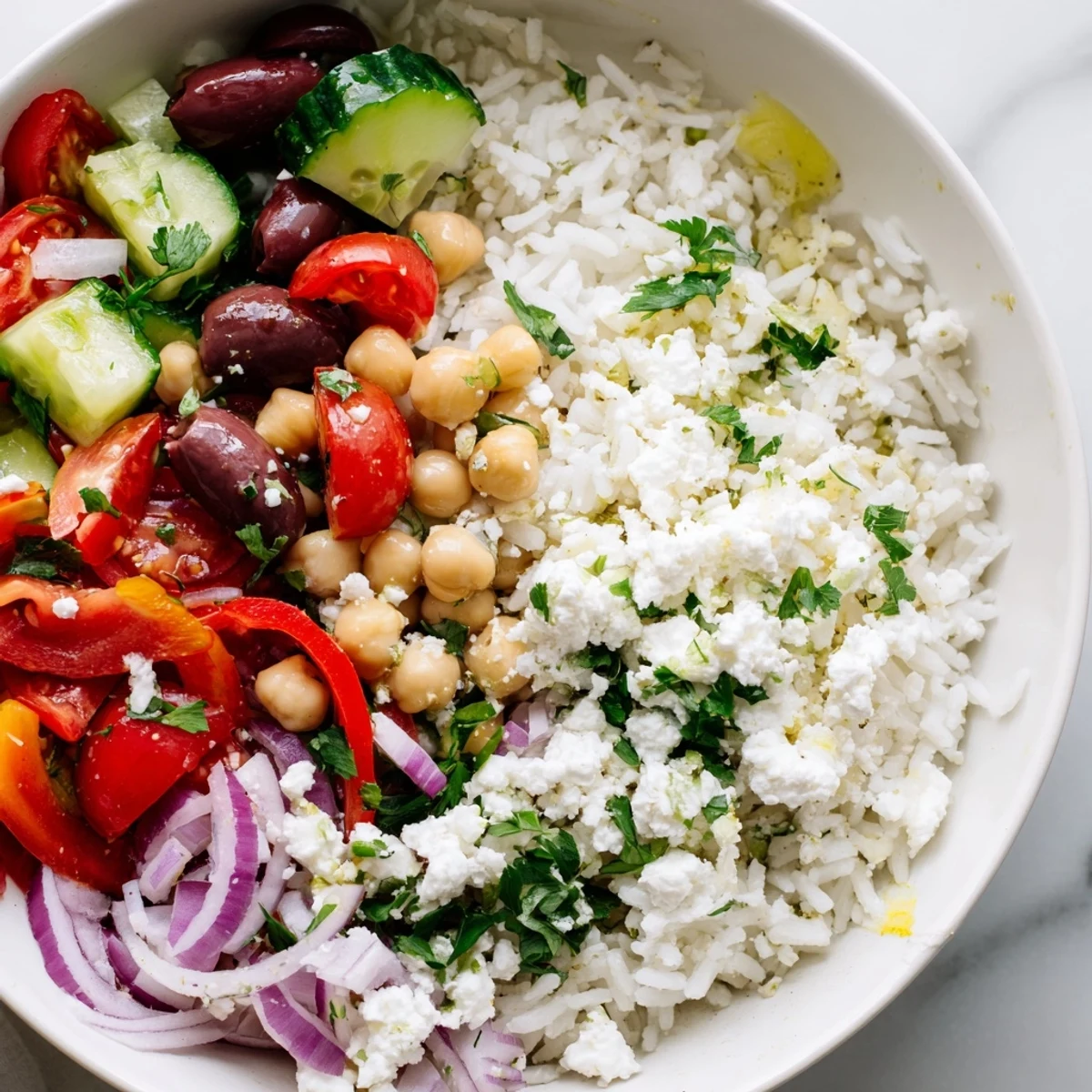Colorful Mediterranean rice bowl topped with crisp vegetables, chickpeas, and crumbled feta cheese