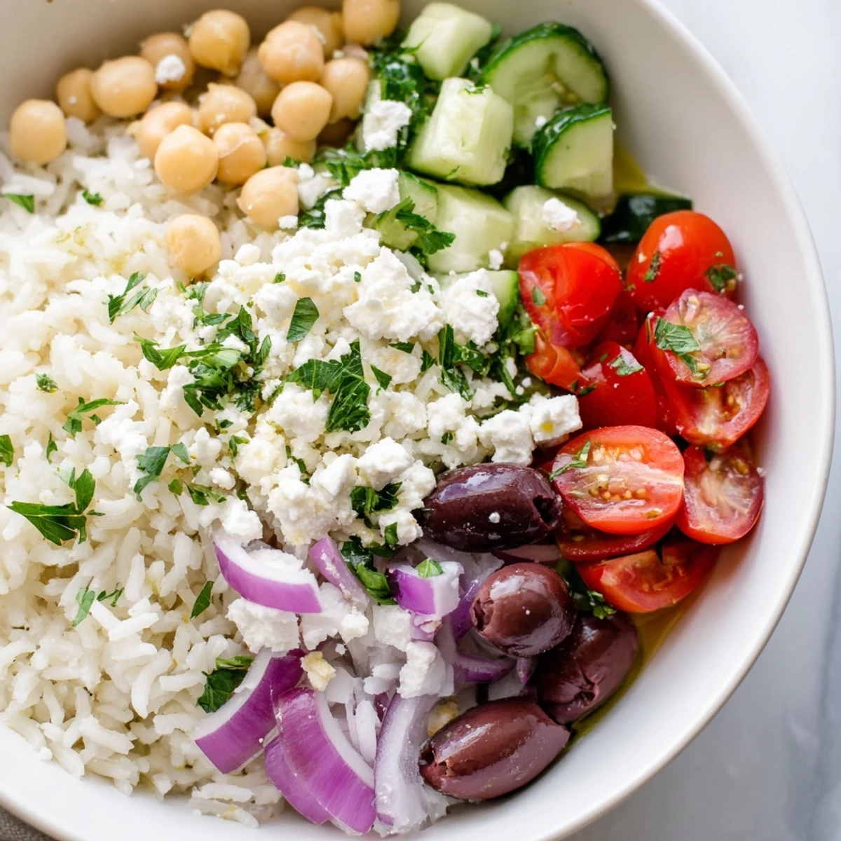 Fresh Mediterranean rice bowl drizzled with lemon herb dressing and vibrant summer produce