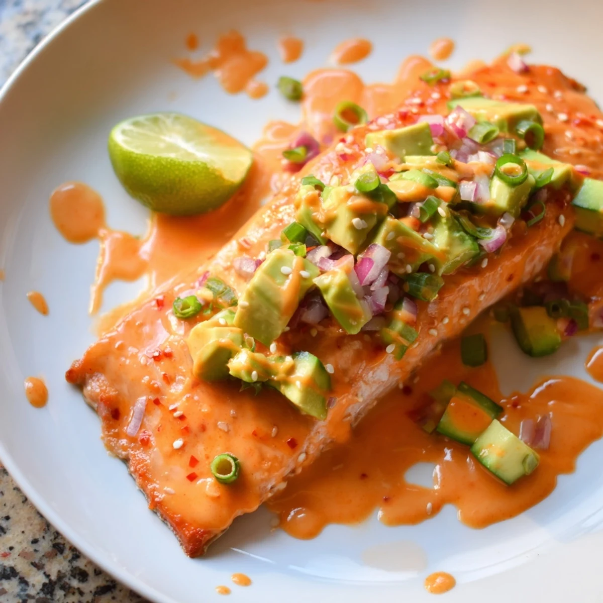 Crispy baked Bang Bang Salmon drizzled with spicy sauce and fresh avocado cucumber salsa