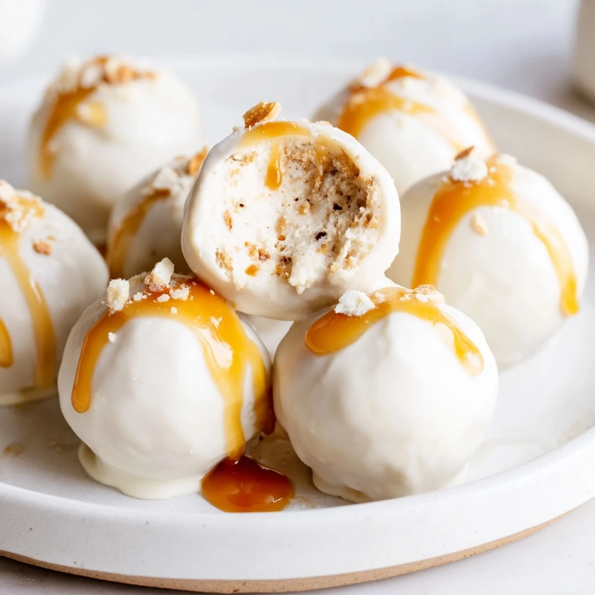 Creamy salted caramel pretzel cheesecake balls drizzled with golden caramel on a rustic tray