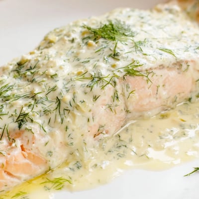 Flaky Baked Salmon with Dill and Lemon Sauce topped with creamy sauce and fresh dill, ready for a family dinner.