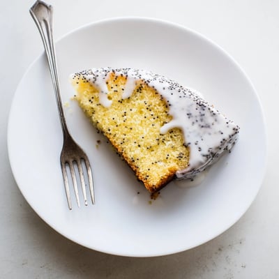 Sliced Lemon Poppy Seed Cake showing moist interior and glistening lemon glaze, perfect for dessert.