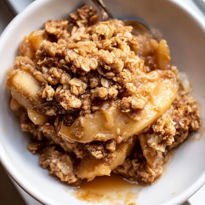 Warm crockpot apple crisp bubbling with caramelized cinnamon apples under a buttery golden oat crumble topping