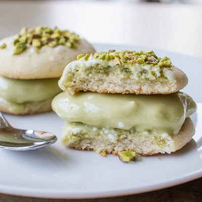 Warm Pistachio Cream Cookies sandwiched with silky nut filling beside teacup